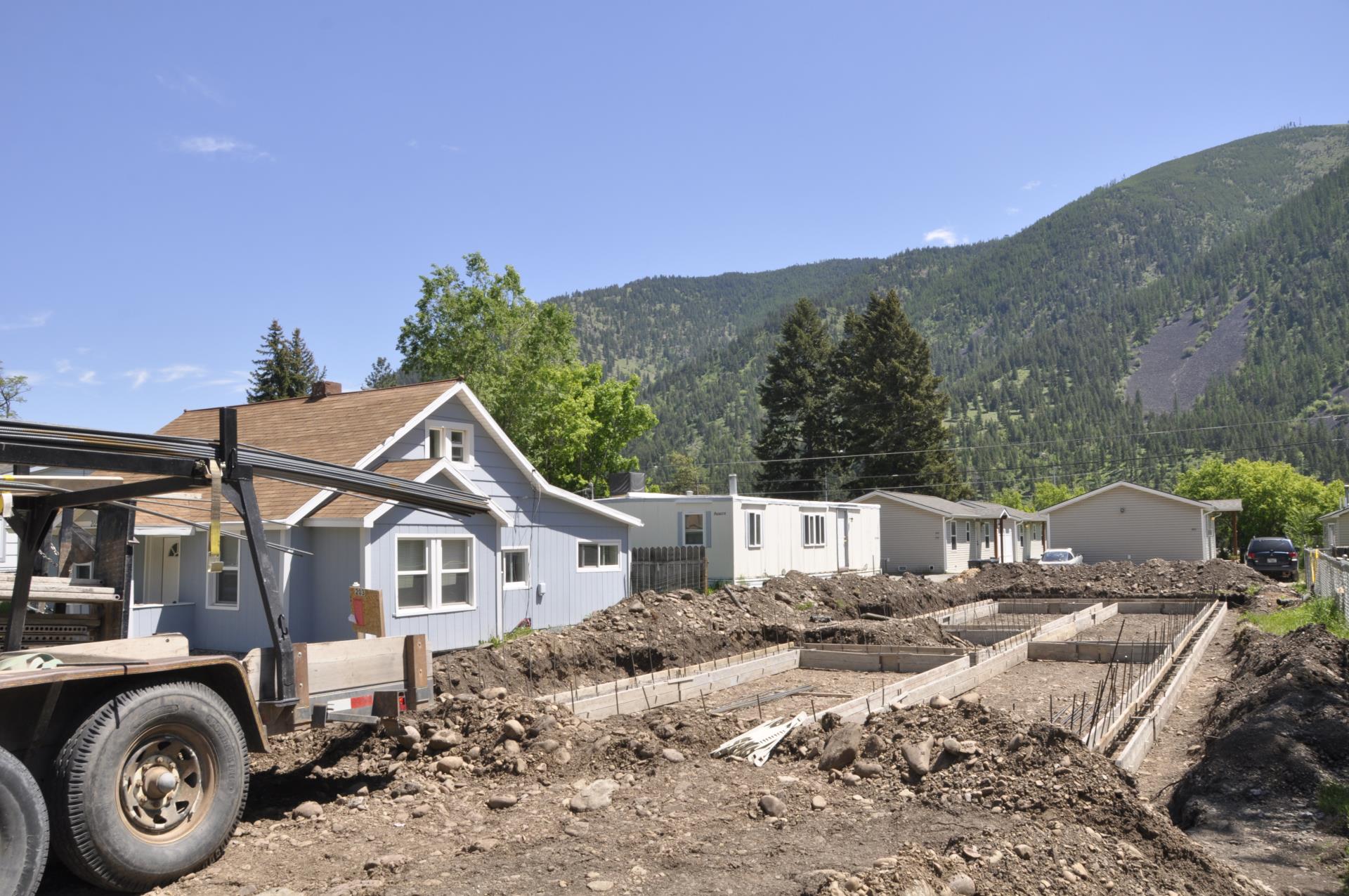 Construction Site With Blue And White Houses And Mountains In Background